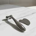 Silver facial roller and gua sha on marble surface